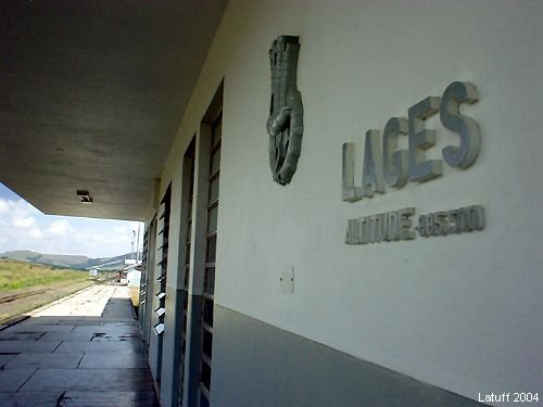 Letreiro em relevo na parede da estação de Lages, com os dizeres LAGES e ALTITUDE 885,300, ao lado de uma pinha de araucária em metal.