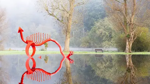 Imagem ilustrativa: Escultura em rio com reflexo e paisagem neblinosa