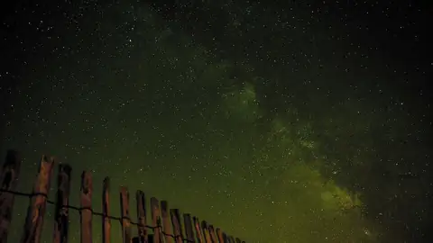 Imagem ilustrativa: Céu noturno com a Via Láctea e cerca de madeira